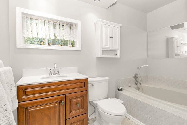 Bathroom featuring toilet, vanity, and a garden tub | Image 15