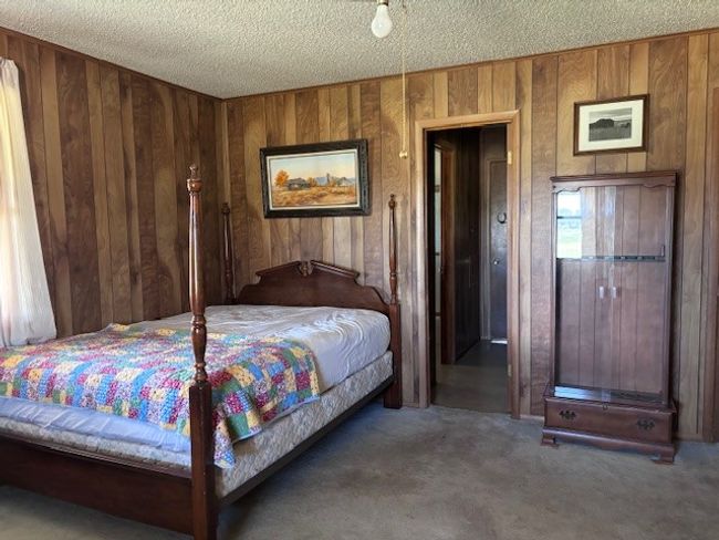 Bedroom with dark carpet, wooden walls, and a textured ceiling | Image 23