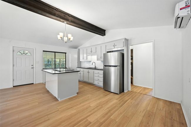 Kitchen featuring freestanding refrigerator, dark countertops, a chandelier, electric cooktop, and an AC wall unit | Image 10