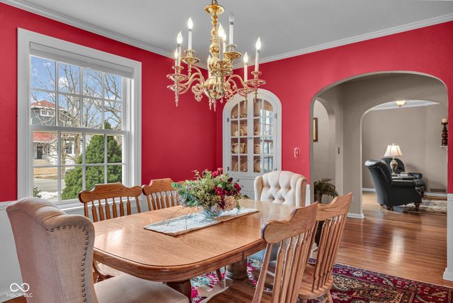 dining space featuring wood finished floors, crown molding, arched walkways, and a notable chandelier | Image 15