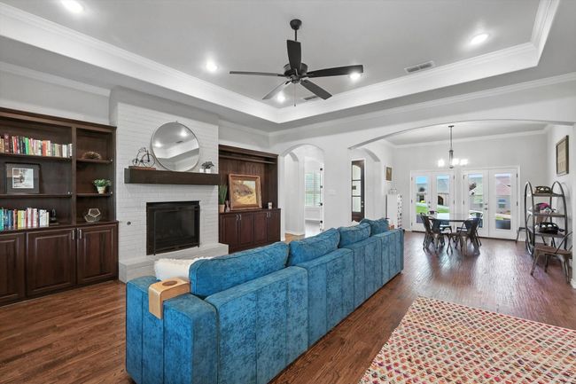 Living room with arched walkways, a chandelier, dark wood-type flooring, a ceiling fan, and a fireplace | Image 12