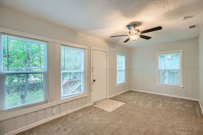 Carpeted foyer with a wainscoted wall, a textured ceiling, visible vents, and ceiling fan | Image 17