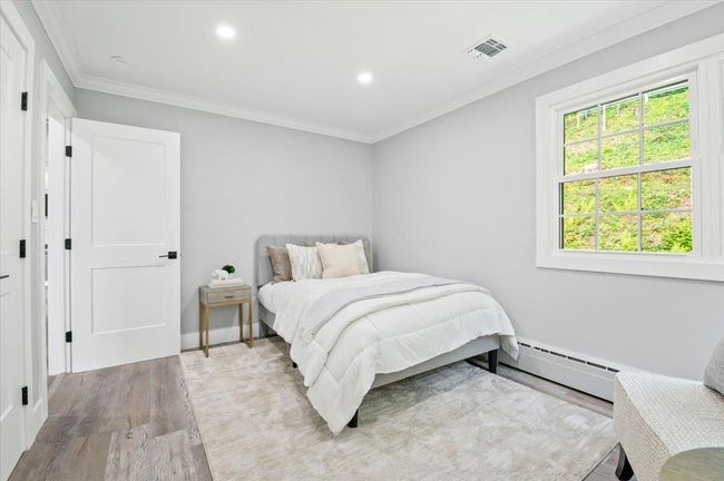 Bedroom featuring wood finished floors, ornamental molding, recessed lighting, and a baseboard heating unit | Image 15