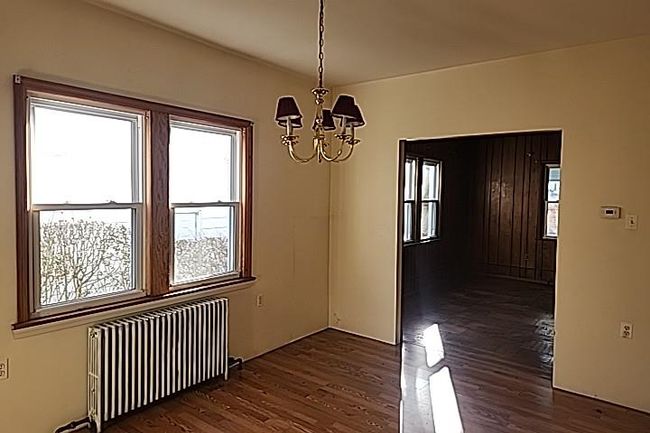 Unfurnished dining area with a chandelier, radiator heating unit, dark hardwood / wood-style floors, and a wealth of natural light | Image 6