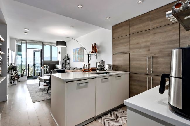 Kitchen featuring a wall of windows, light wood finished floors, a sink, light countertops, and modern cabinets | Image 4