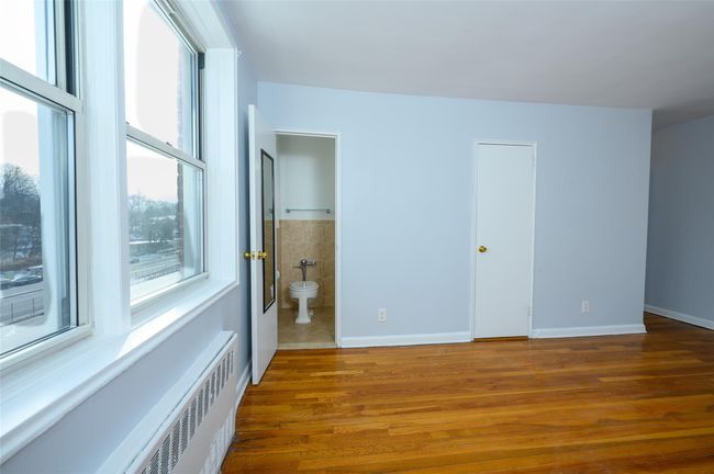 Unfurnished bedroom with hardwood / wood-style flooring, ensuite bath, a baseboard radiator, and radiator | Image 13