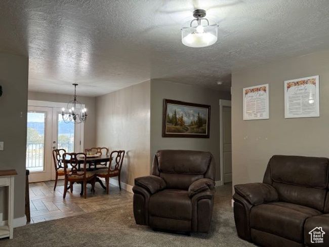 Living room featuring a textured ceiling, baseboards, and an inviting chandelier | Image 10