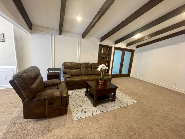 Living room with a decorative wall, beamed ceiling, french doors, and carpet | Image 4