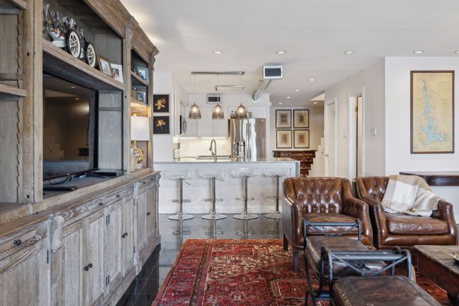 Spacious living area with fireplace, looking at kitchen and entryway. | Image 15