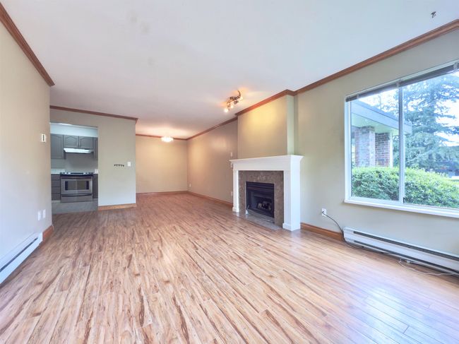 Unfurnished living room with crown molding, a baseboard heating unit, light wood finished floors, a fireplace, and baseboards | Image 6