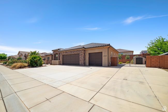 View of front of property with a tiled roof, a gate, fence, an attached garage, and stucco siding | Image 4