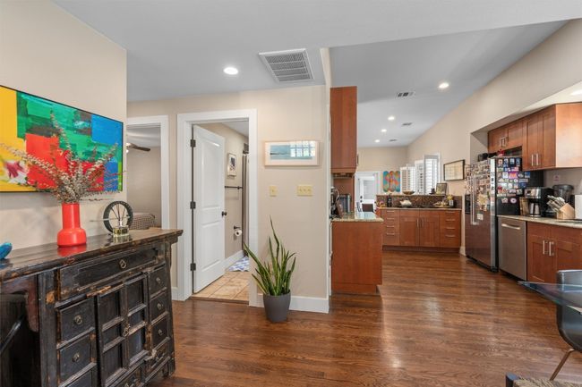 Kitchen with dark wood-style floors, visible vents, brown cabinetry, and appliances with stainless steel finishes | Image 4