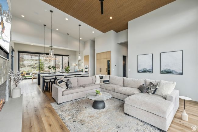 Living area with recessed lighting, a high ceiling, wooden ceiling, light wood-style floors, and a fireplace | Image 22