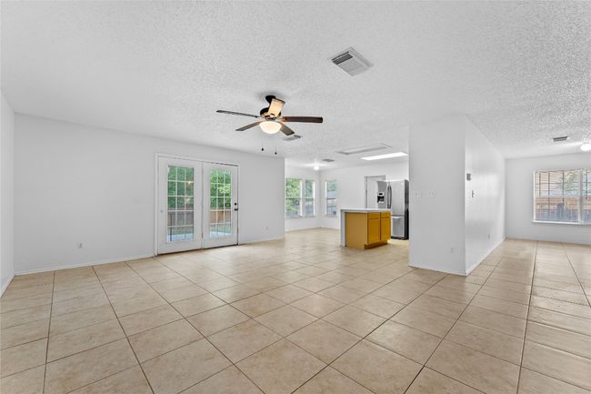 Unfurnished living room featuring a textured ceiling, a ceiling fan, light tile patterned floors, and baseboards | Image 7