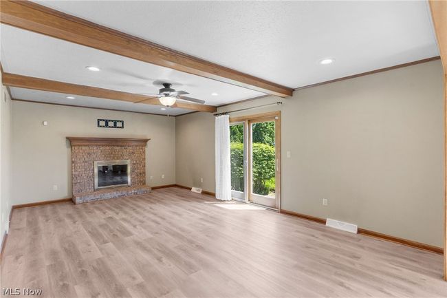 Unfurnished living room featuring ceiling fan, beam ceiling, light hardwood / wood-style flooring, and a fireplace | Image 12