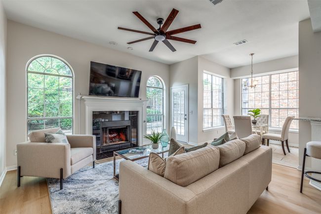Living room with ceiling fan, light wood-type flooring, a premium fireplace, a chandelier, and baseboards | Image 4
