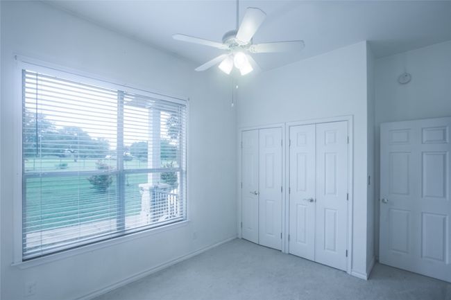 Unfurnished bedroom featuring light colored carpet, multiple closets, and ceiling fan | Image 13