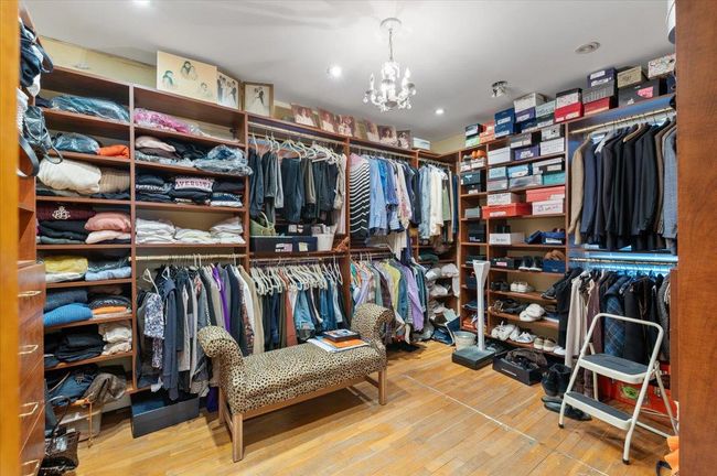 Spacious closet with a notable chandelier and wood finished floors | Image 18