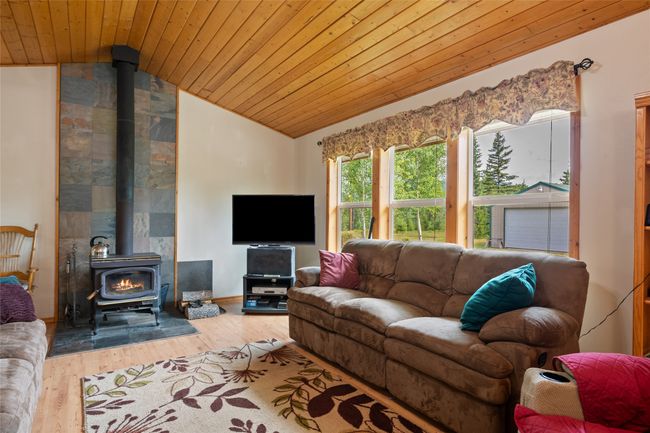 Living room with a wood stove, lofted ceiling, wood ceiling, and wood finished floors | Image 22