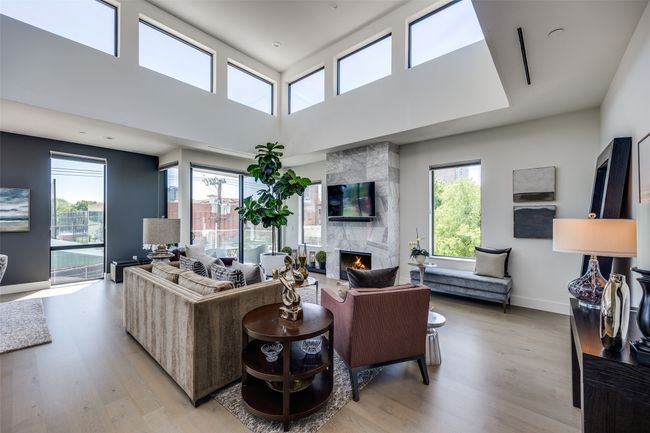 Living area featuring a high end fireplace, a high ceiling, light wood finished floors, and baseboards | Image 4