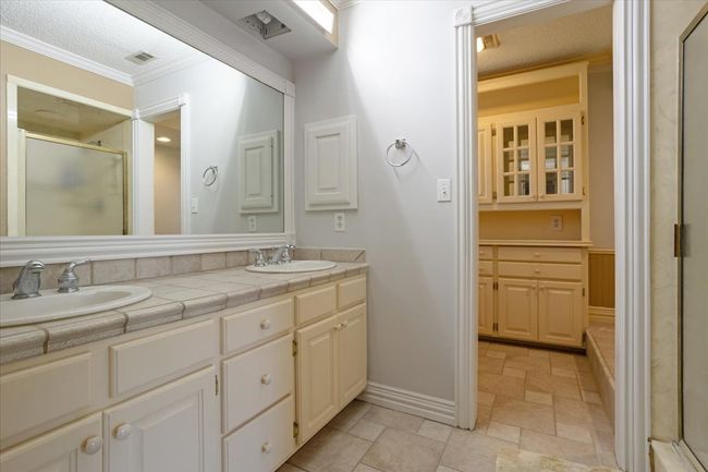Bathroom with crown molding, double vanity, stone tile flooring, and a stall shower | Image 17