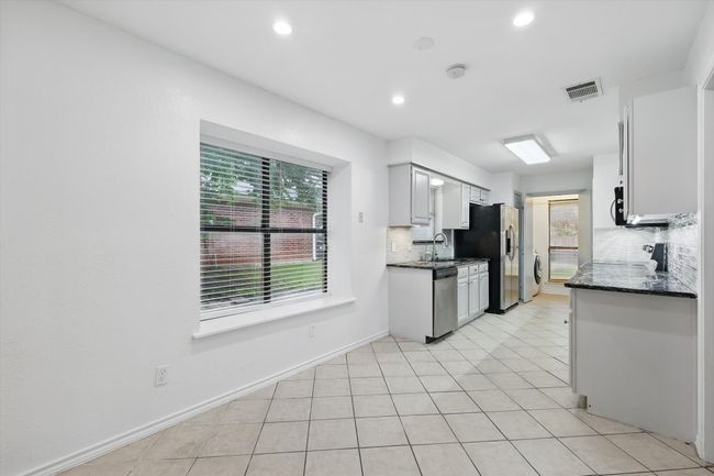 Kitchen featuring stainless steel appliances, tasteful backsplash, recessed lighting, light tile patterned flooring, and dark stone counters | Image 10