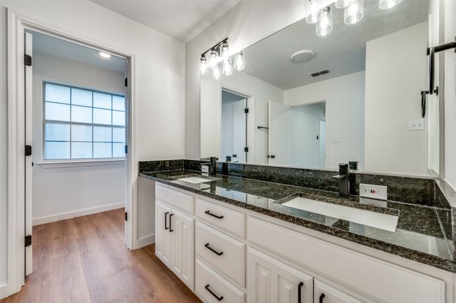 Full bath featuring wood finished floors, double vanity, a sink, and visible vents | Image 25