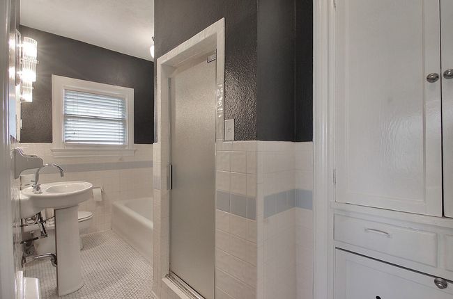 Bathroom featuring tile patterned flooring, tile walls, toilet, an enclosed shower, and wainscoting | Image 9