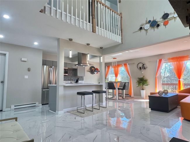 Living area featuring recessed lighting, a baseboard radiator, marble finish floor, baseboards, and a high ceiling | Image 28