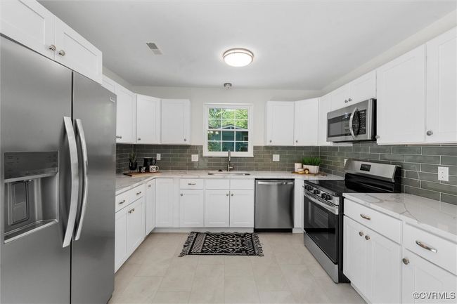 Remodeled kitchen with new cabinets, quartz tops, green subway tile backsplash, and new stainless appliances | Image 10