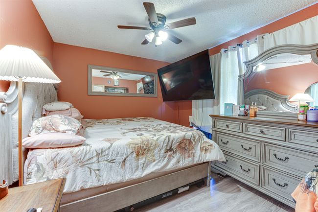 Bedroom featuring wood finished floors, a textured ceiling, and ceiling fan | Image 5