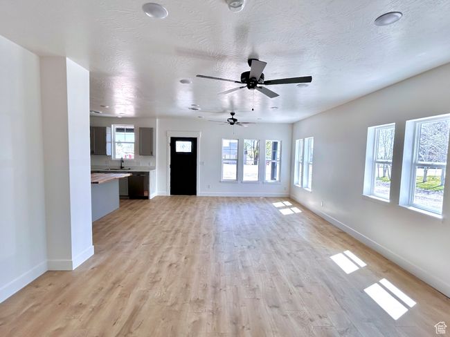 Unfurnished living room featuring baseboards, ceiling fan, light wood-style floors, and a sink | Image 29