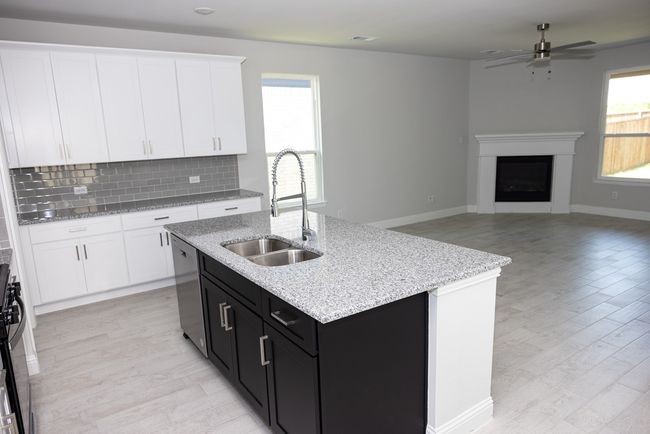 Kitchen featuring dishwasher, a fireplace, white cabinets, ceiling fan, and light wood-style flooring | Image 5