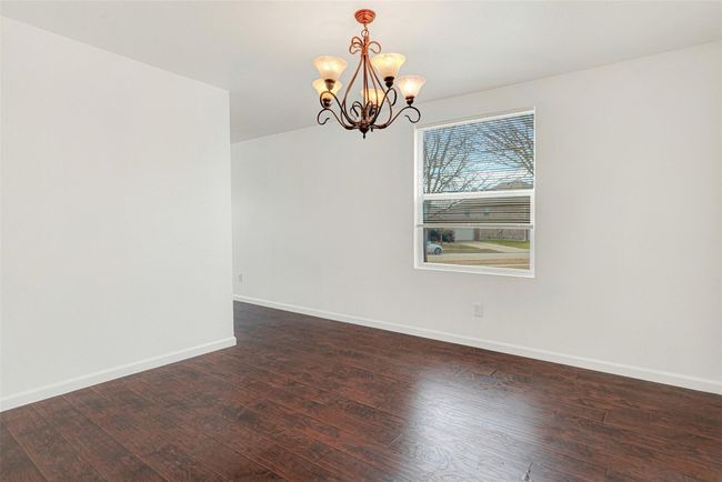 Unfurnished room featuring a chandelier, dark wood-style floors, and baseboards | Image 10
