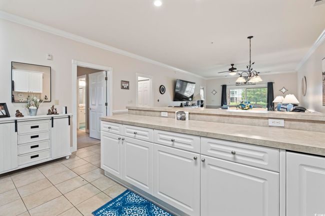Kitchen featuring crown molding, light tile patterned floors, light countertops, white cabinets, and ceiling fan | Image 18
