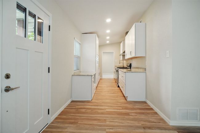 Stunning galley kitchen with custom wood cabinetry, granite countertops, built-in pantry, and upgraded fitxures. | Image 5