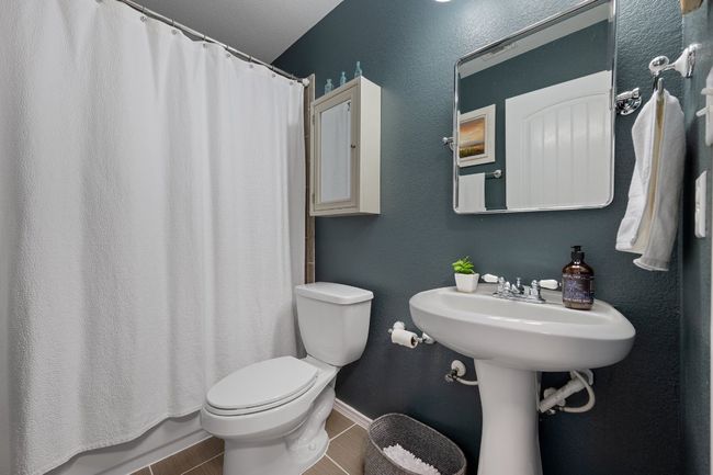 Bathroom with baseboards, a shower with curtain, and toilet | Image 14