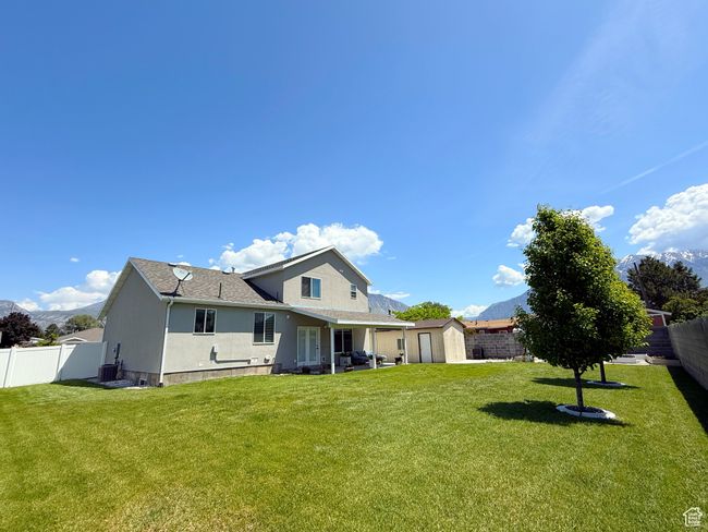 Back of house with a storage unit, a fenced backyard, stucco siding, a shingled roof, and a mountain view | Image 23