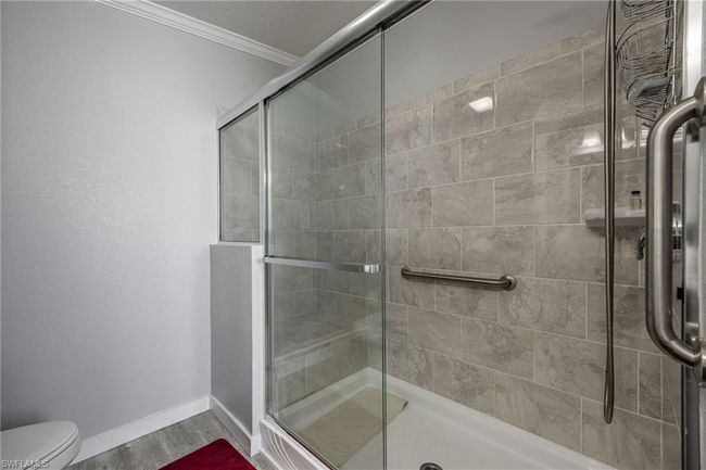 Full bath with a shower stall, baseboards, toilet, ornamental molding, and wood finished floors | Image 26