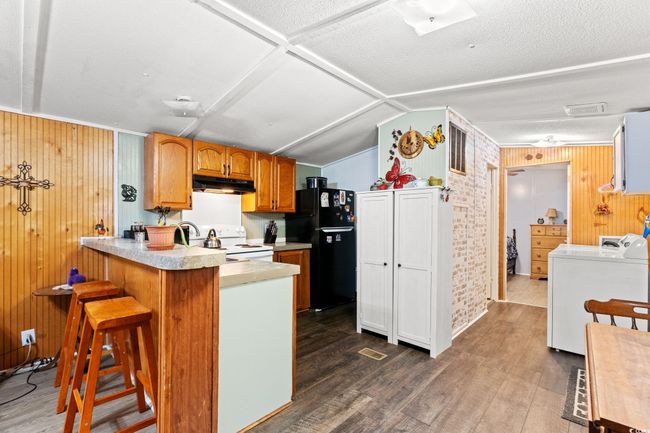 Kitchen featuring white range with electric stovetop, freestanding refrigerator, under cabinet range hood, a peninsula, and light countertops | Image 9