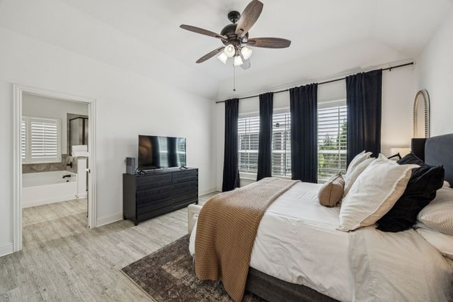 Bedroom with vaulted ceiling, light wood-style floors, ensuite bathroom, and a ceiling fan | Image 9