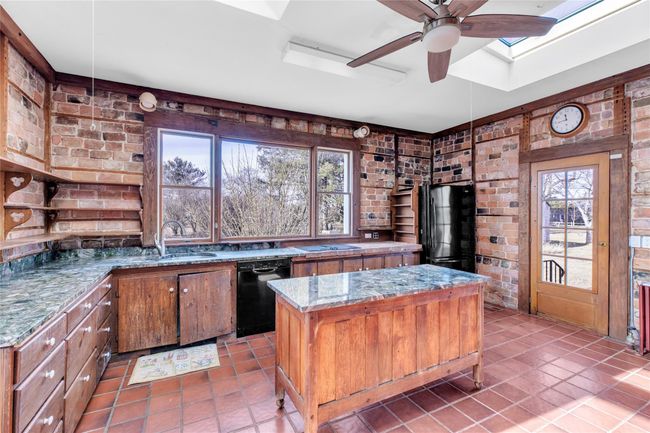 Kitchen featuring a center island, brick wall, and black appliances | Image 14