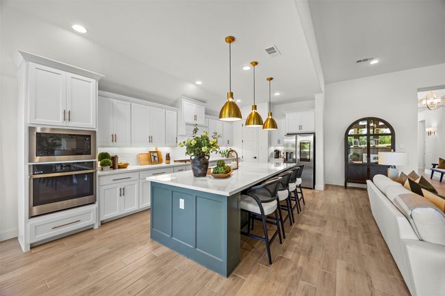 Kitchen with appliances with stainless steel finishes, white cabinetry, a breakfast bar area, light wood-type flooring, and light countertops | Image 9