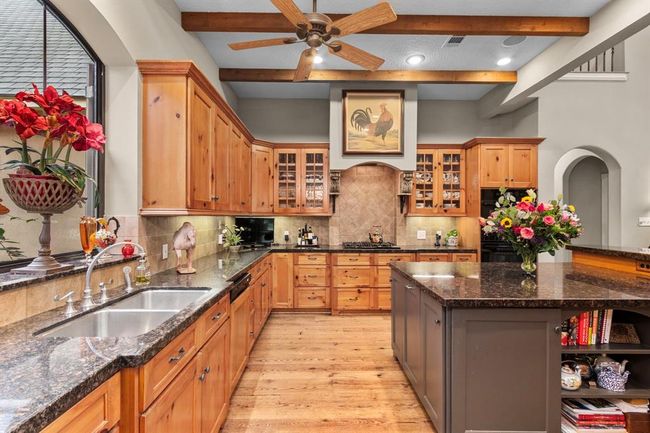 The heart of every home, this generously-sized gourmet kitchen features state of the art appliances including a Viking gas stove, SubZero refrigerator and freezer clad in custom wood panels and hardware, KitchenAid dishwasher and gas ovens, as well as a U Line ice machine with custom wood panel. The wide window perched above the kitchen sink offers an enchanting view of the grounds, making even mundane tasks like dishwashing, serene. | Image 12