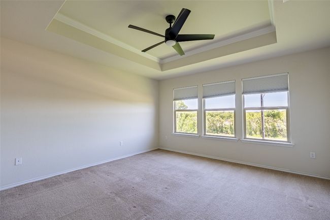 Spare room featuring crown molding, a raised ceiling, carpet flooring, and a ceiling fan | Image 12