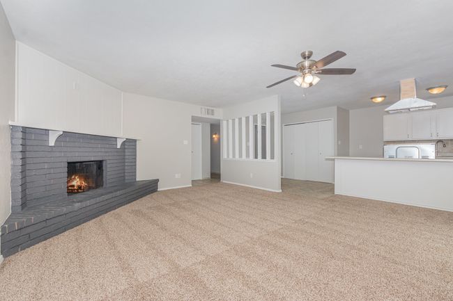 Unfurnished living room featuring a fireplace, light carpet, and a ceiling fan | Image 5
