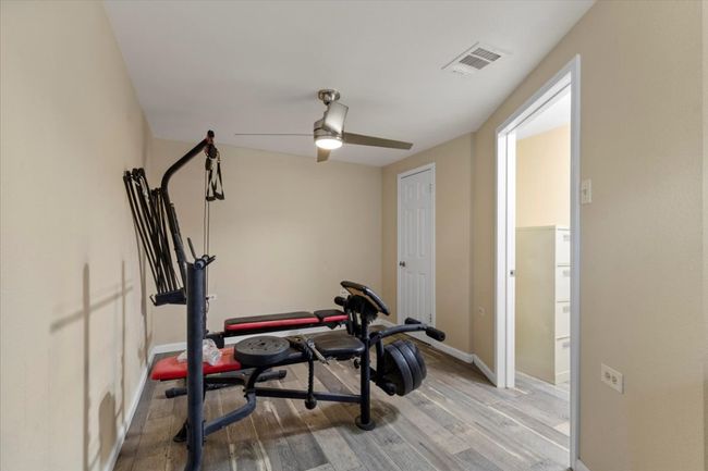 Workout room with a ceiling fan, baseboards, visible vents, and light wood finished floors | Image 19