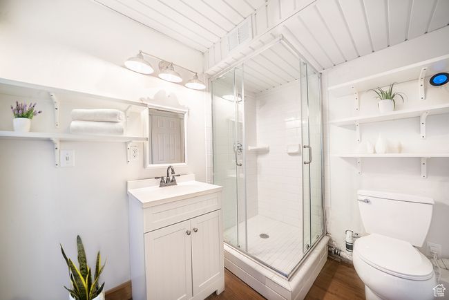 Bathroom featuring toilet, a stall shower, wood finished floors, and vanity | Image 11