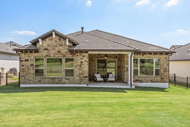 Rear view of house with stone siding, ceiling fan, a patio, and a tile roof | Image 37