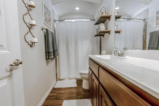 Bathroom featuring curtained shower, vanity, toilet, and wood finished floors | Image 13